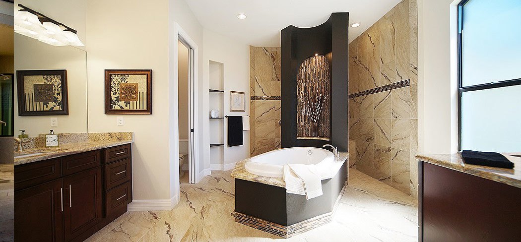 Primary bath with a soaking tub, stone-look tile walls and a dark wood vanity